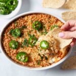 Jalapeño popper party dip being scooped up with a tortilla chip.