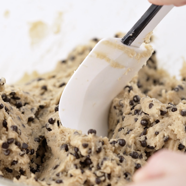 Chocolate chips being folded into cookie batter to make Levain chocolate chip cookies.