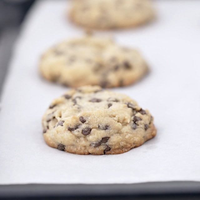 Levain chocolate chip cookies freshly baked on a baking sheet lined with parchment paper.