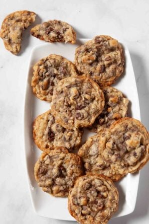 Overhead shot of coconut chocolate chip cookies on a white platter on a marbled surface.