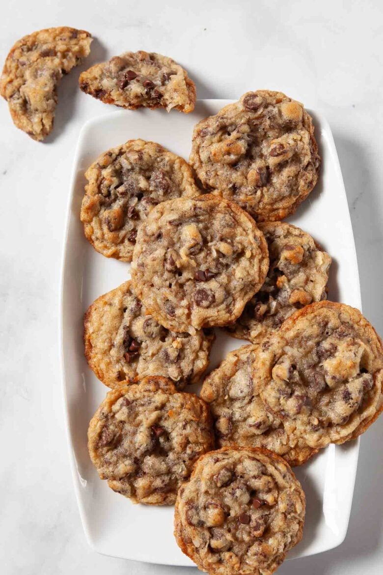 Overhead shot of coconut chocolate chip cookies on a white platter on a marbled surface.