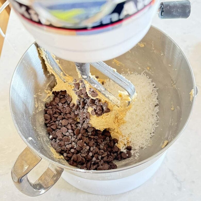 Chocolate chips and coconut in cookie batter to make coconut chocolate chip cookies.