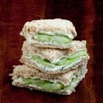 Cucumber sandwiches cut into triangles stacked on top of each other.