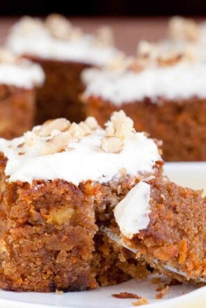 Carrot cake with cream cheese frosting sliced into a square piece and a fork digging into it.
