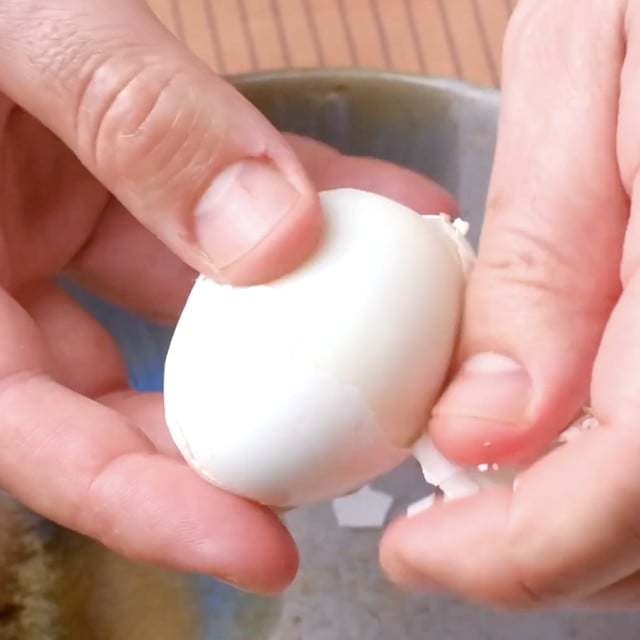A hand peeling eggs.