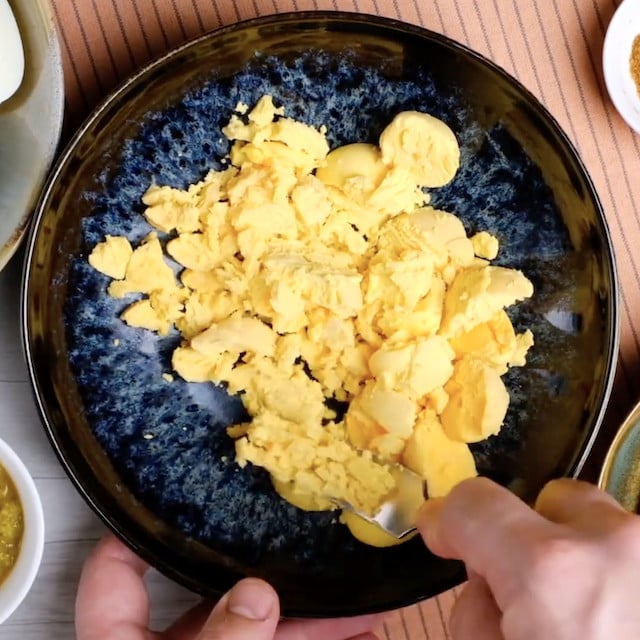 Egg yolks being mashed to make deviled eggs at home.