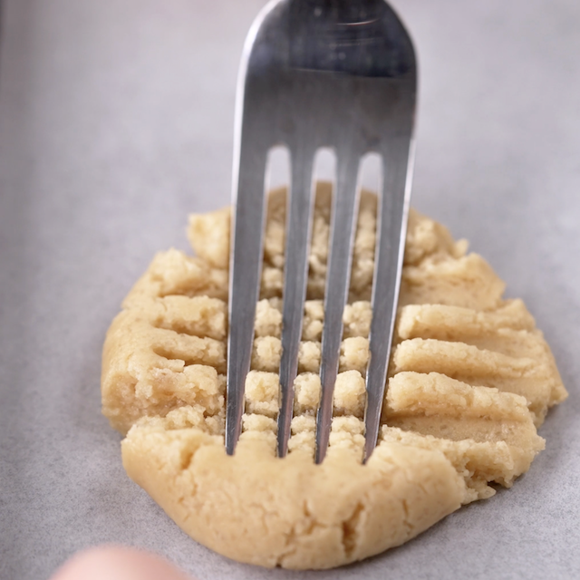 Criss cross being marked with a fork to make peanut butter sandwich cookies.