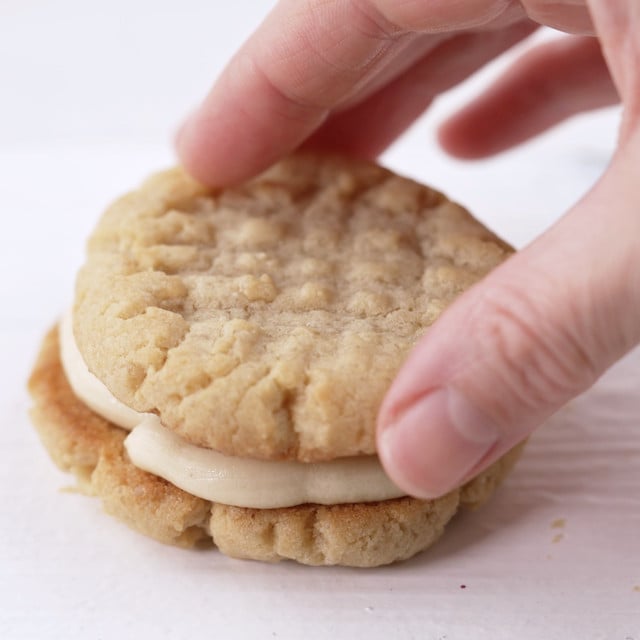 A hand stacking a cookie to make a peanut butter sandwich cookie.