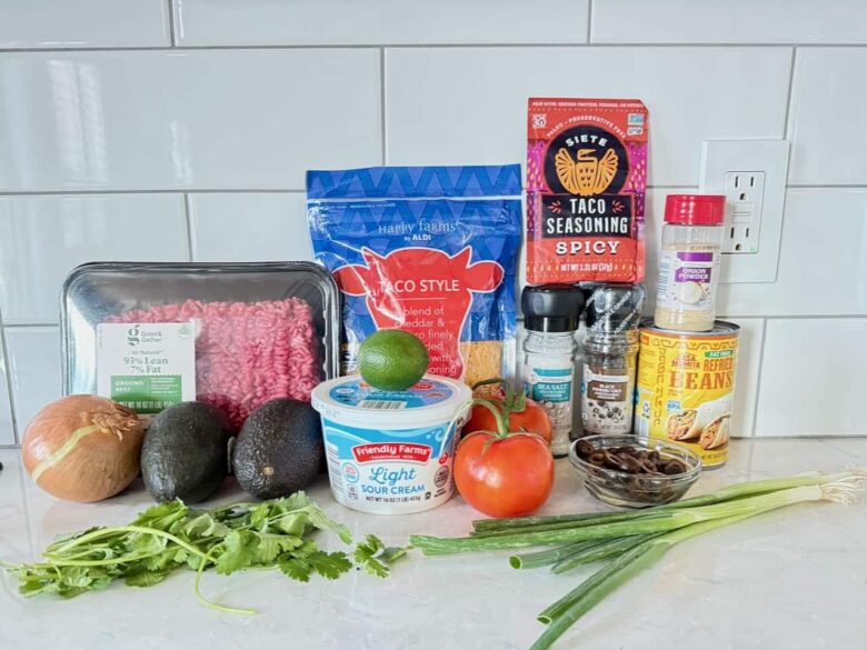 Ingredients to make 7 layer mexican dip on a white kitchen counter.