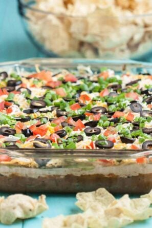 Side shot of 7 layer mexican dip with tortilla scoop chips on the side.