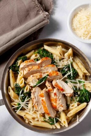 Overhead shot of chicken florentine pasta in a bowl with extra cheese on the side.