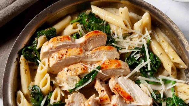 Overhead shot of chicken florentine pasta in a bowl with extra cheese on the side.