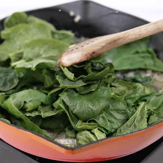 Spinach being wilted to make chicken florentine pasta.