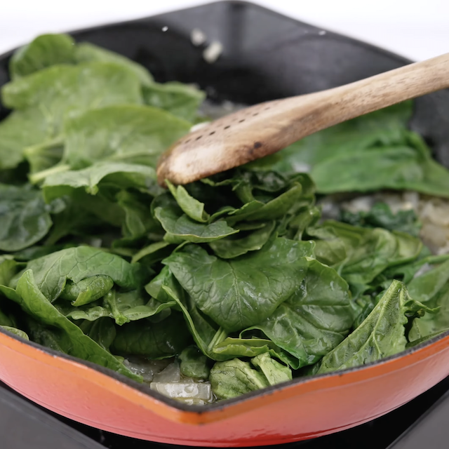Spinach being wilted to make chicken florentine pasta.