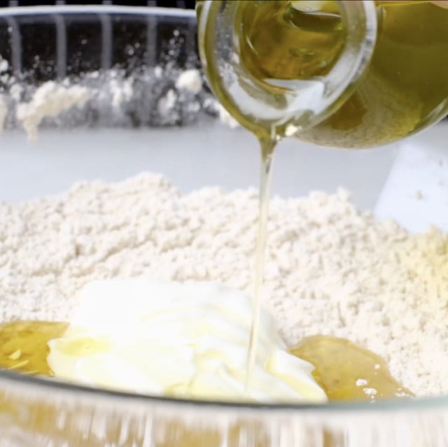 Wet ingredients to make garlic naan being poured into bowl.