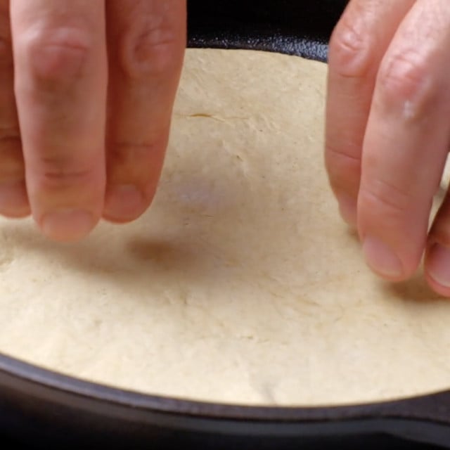 Garlic naan being cooked on a skillet.