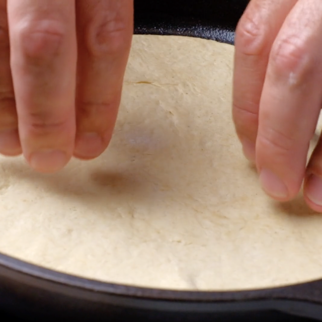 Garlic naan being cooked on a skillet.