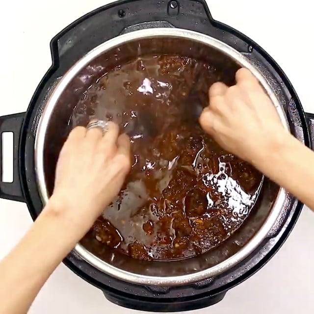 Instant pot beef barbacoa being shredded.