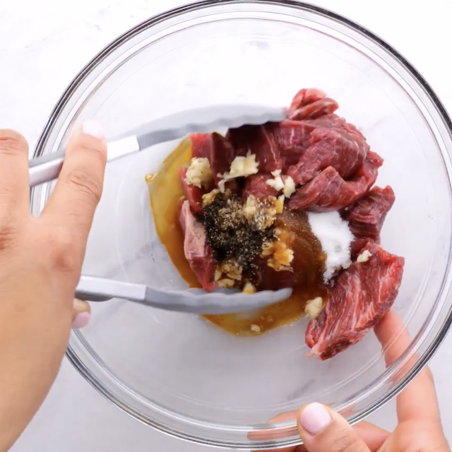 Beef being mixed with marinade ingredients to make japchae.