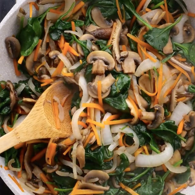 Japchae vegetables being cooked in a pan prior to adding to the noodles.