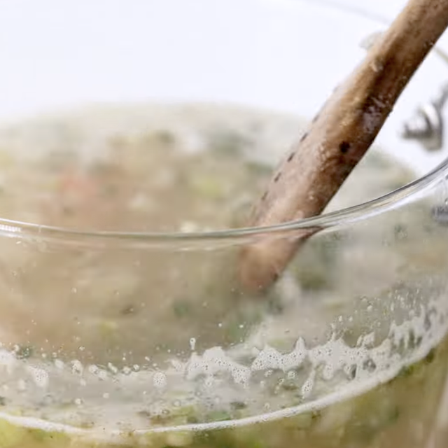 Lemon chicken soup broth simmering in a glass pot.