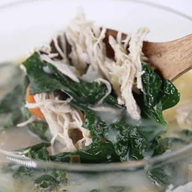 A ladle holding some lemon chicken soup.