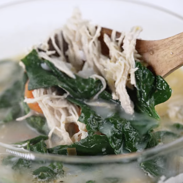 A ladle holding some lemon chicken soup.