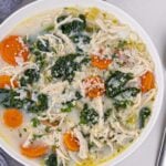 lemon chicken soup in a bowl with spoon on the side.