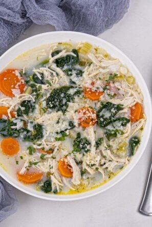 lemon chicken soup in a bowl with spoon on the side.