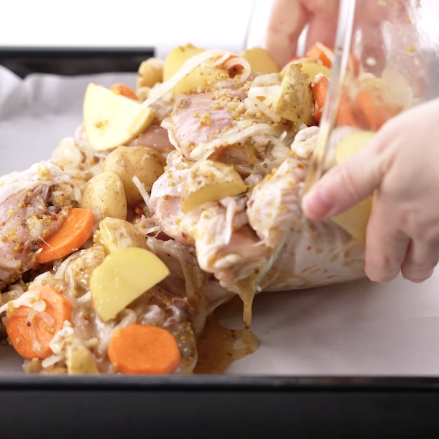 sheet pan chicken and potatoes being added to a pan to roast.