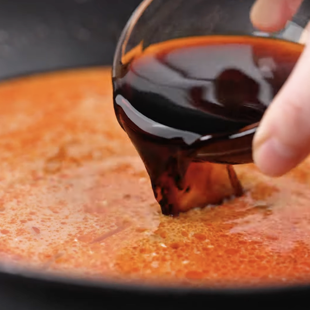 Fish sauce being added to make thai curry noodles in a pot.
