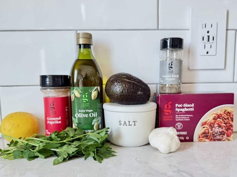 Ingredients to make avocado pasta at home on a white kitchen counter.