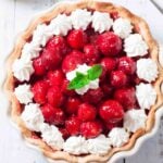 Overhead shot of a fresh strawberry pie with piped whipped cream.