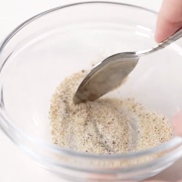 Seasoning to make lemon chicken orzo being mixed in a bowl.