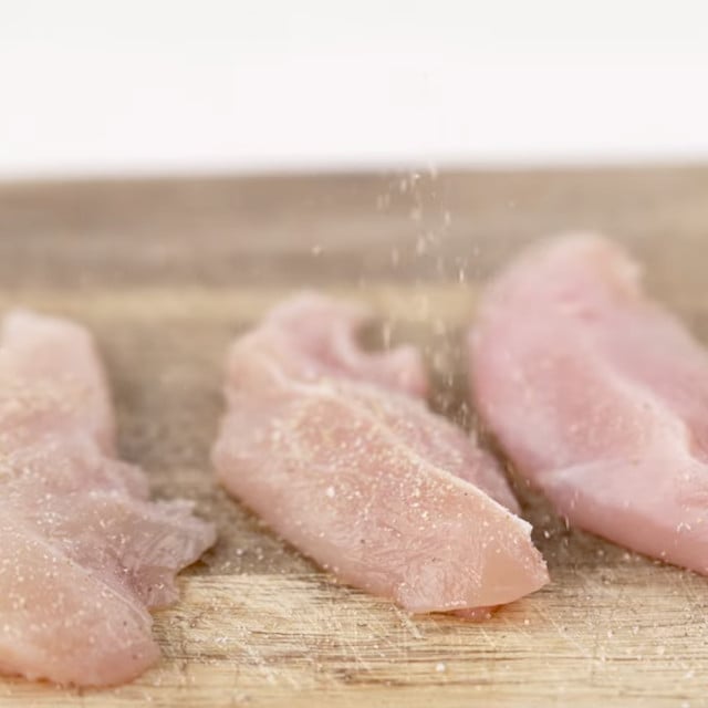 Chicken being seasoned to make lemon chicken orzo.