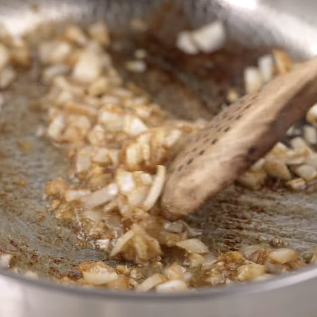Onion and garlic being sauteed in a pan.