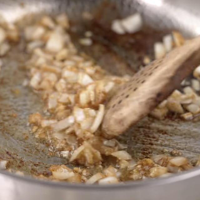 Onion and garlic being sauteed in a pan.