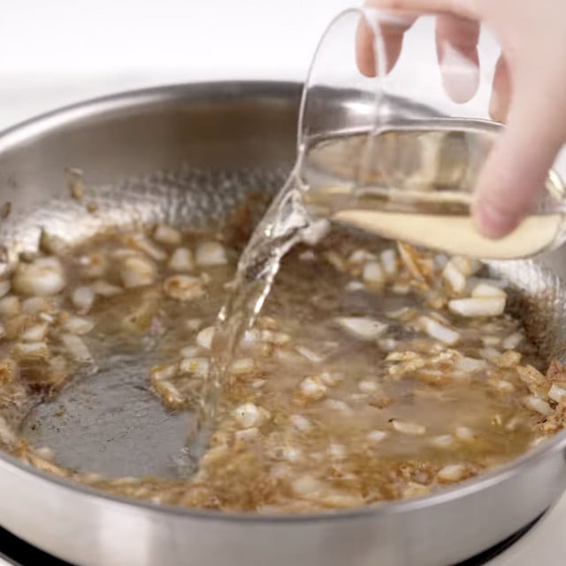 Broth being poured into pan to make sauce for lemon chicken orzo.