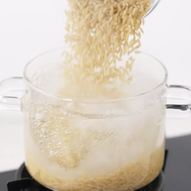 Orzo being added to water to boil.