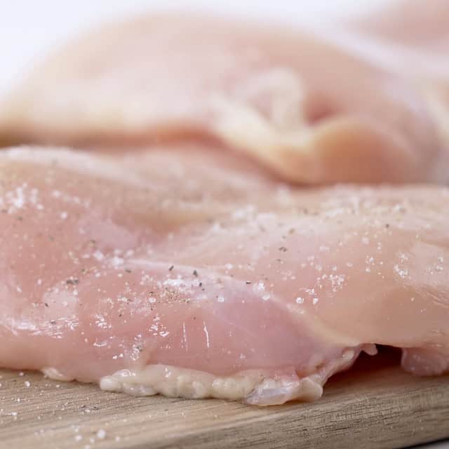 Chicken being seasoned to make lemon chicken pasta.