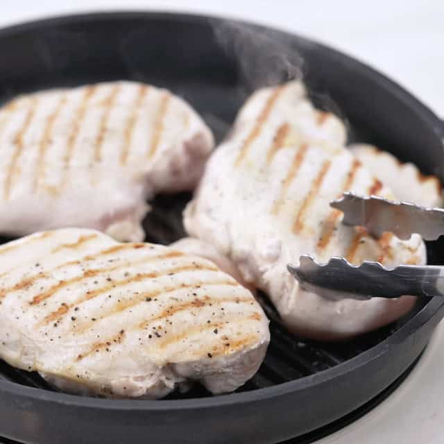 Chicken being grilled in a skillet to make lemon chicken pasta.