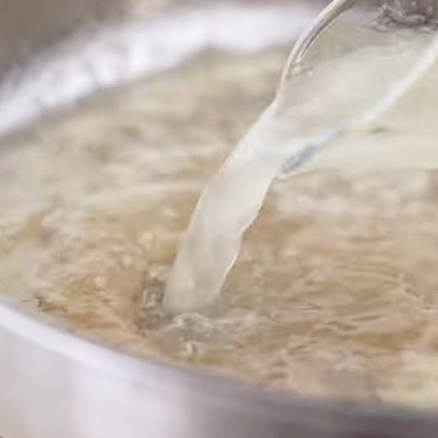 Broth being added to a pan to make lemon chicken pasta sauce.