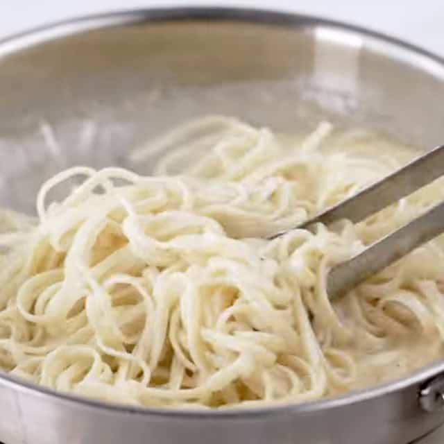 Pasta being tossed with homemade lemon sauce to make lemon chicken pasta.