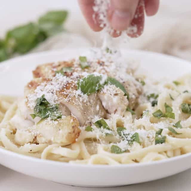 Cheese being sprinkled on top of freshly made lemon chicken pasta.