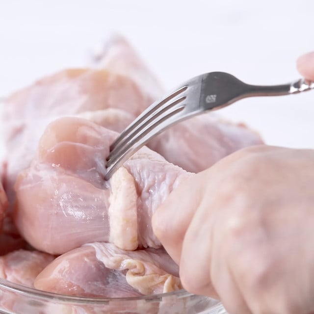 Chicken being poked to prep it for marinade to make lemon garlic chicken.