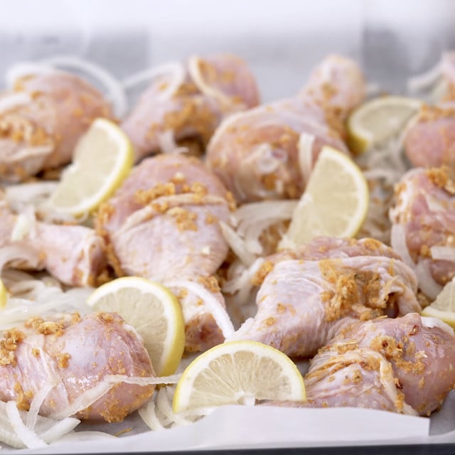 Lemon garlic chicken with lemon slices on a baking sheet.