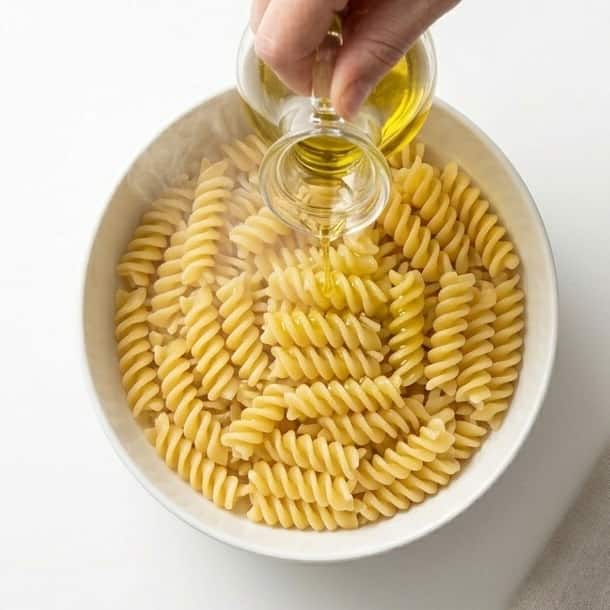Pasta being tossed with olive oil to make easy summer pasta salad.