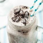 Close up of Blizzard Oreo Dessert in a clear mug with handle with two white and green straws coming out of the drink.