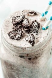 Close up of Blizzard Oreo Dessert in a clear mug with handle with two white and green straws coming out of the drink.