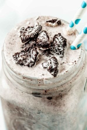 Close up of Blizzard Oreo Dessert in a clear mug with handle with two white and green straws coming out of the drink.
